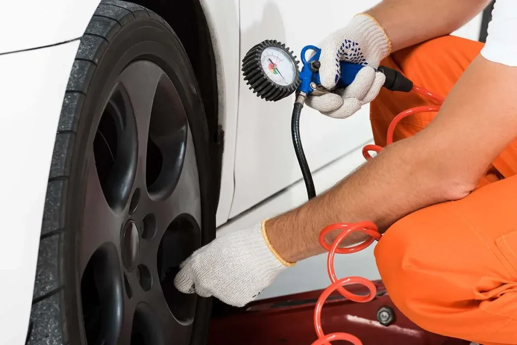 Auto technician checking tire pressure