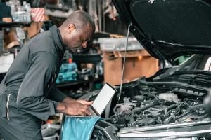 Mechanic using a laptop to perform maintenance on a vehicle