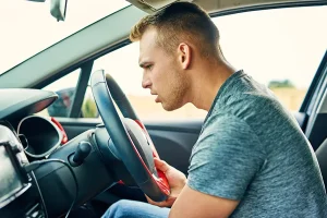 A young man having troubles with his car while driving.