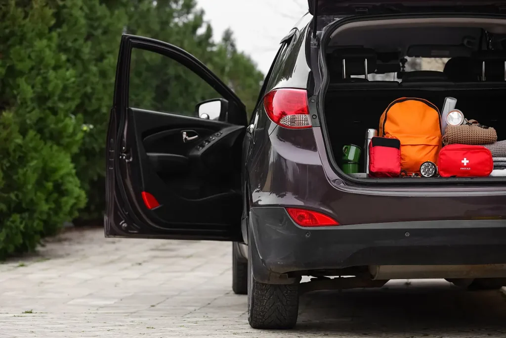 Emergency backpack, first aid kit and necessities in trunk of car outdoors