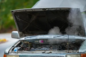 Car with hood up and engine steaming.